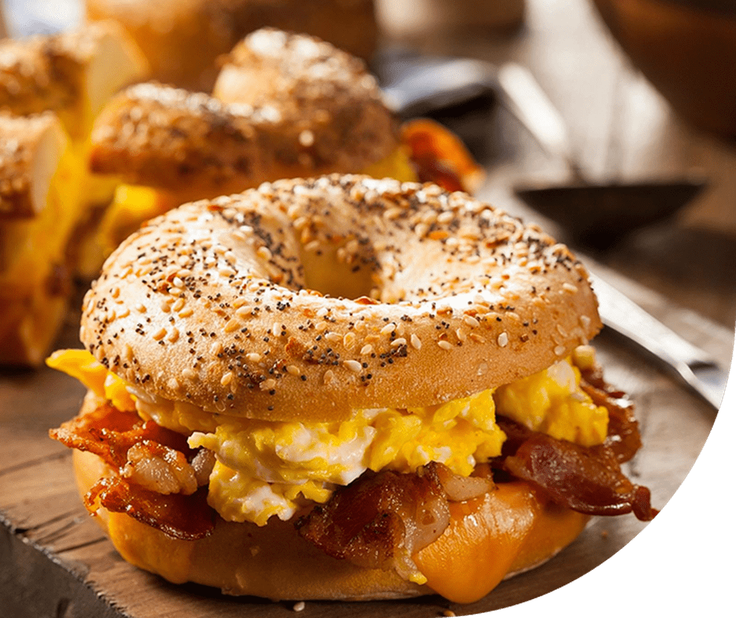 A bagel sandwich with bacon and eggs on it.