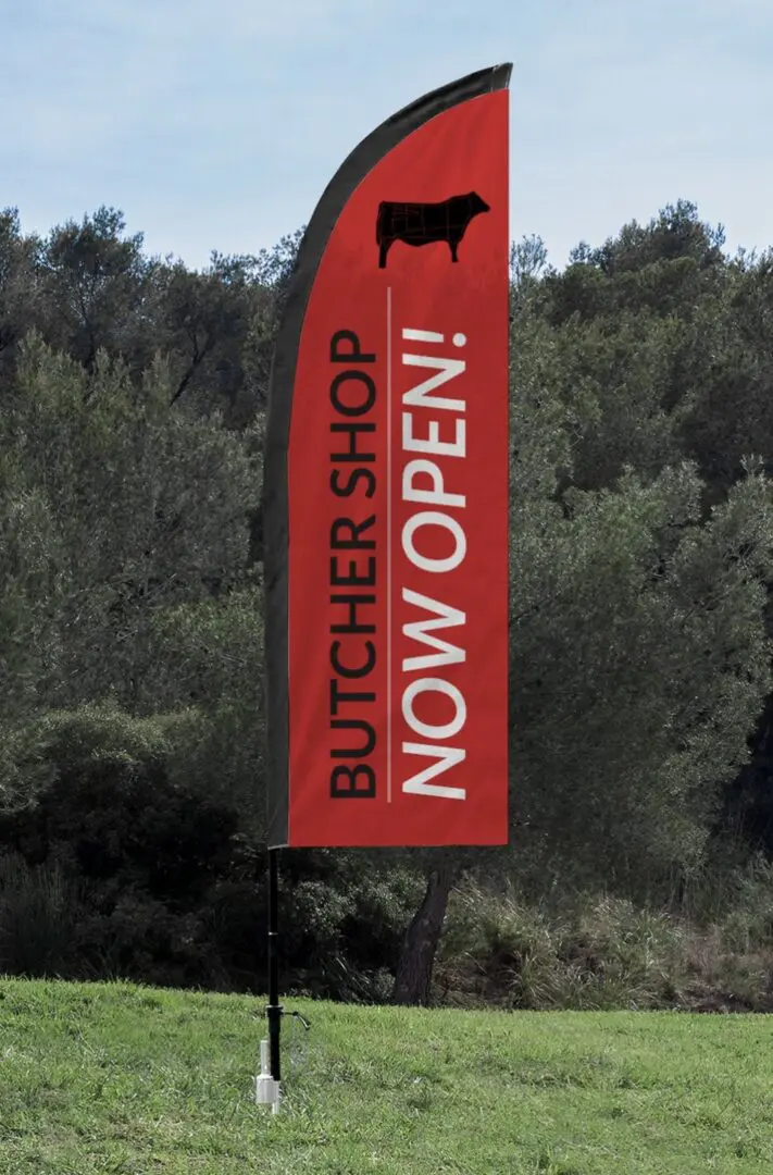 A red banner with the words " butcher shop now open !" on it.