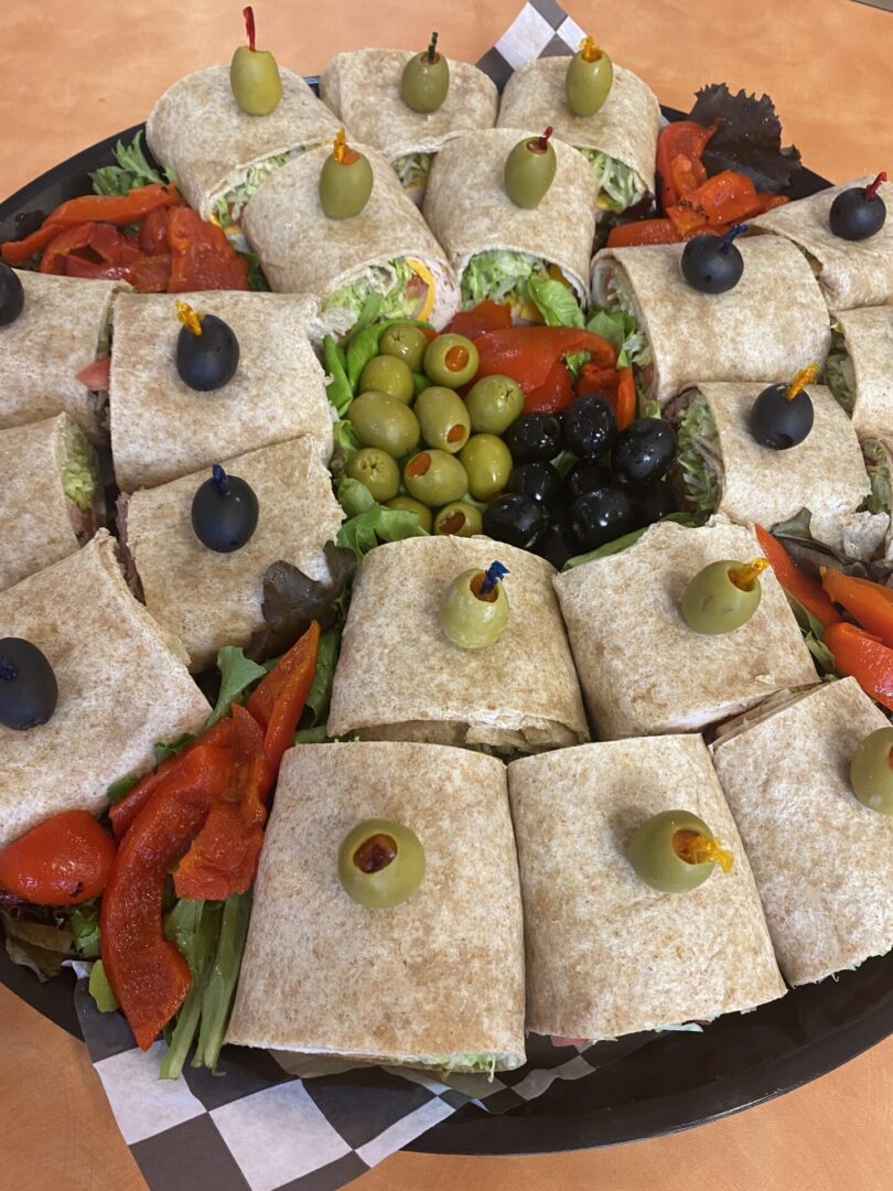 A platter of sandwiches and olives on top of a table.